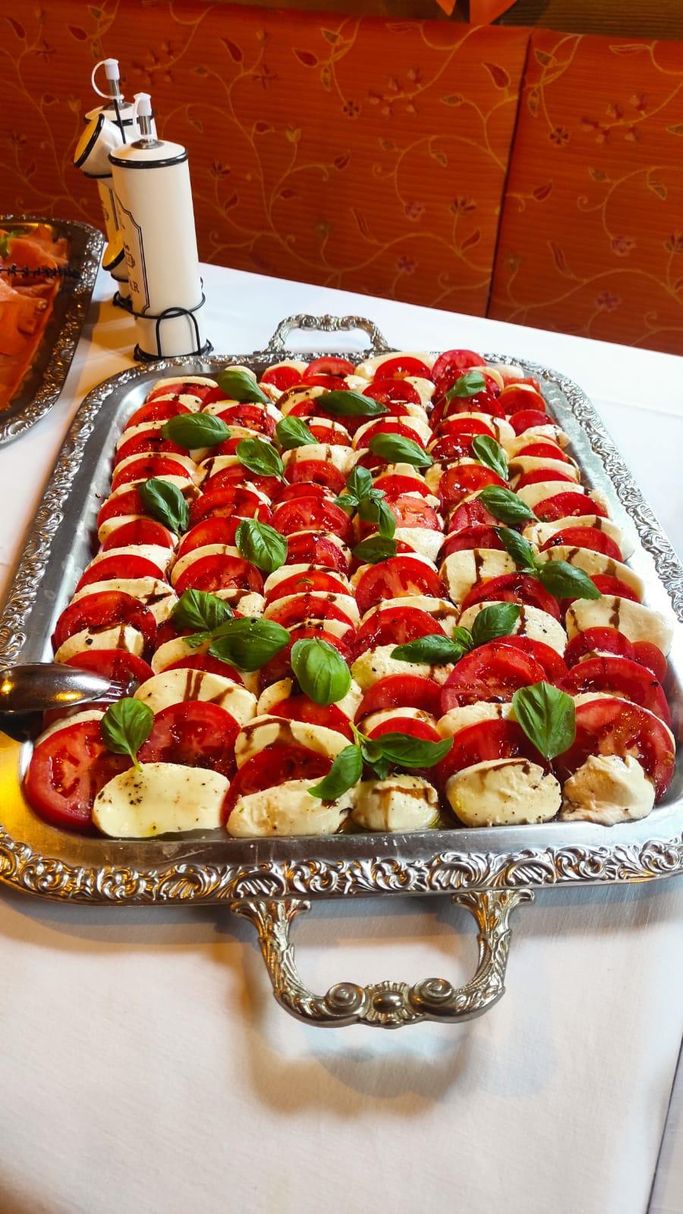 Eine Tomaten-Morzarella-Platte steht auf einem weiß eingedeckten Tisch.