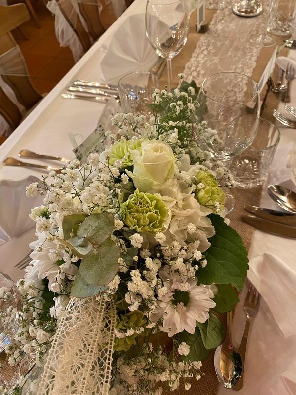 Hochzeits Blumengesteck auf einer langen weißen Tafel.