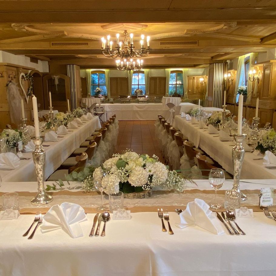 Ein großer Raum mit Tischen und Stühlen, festlich gedeckt für ein Abendessen.